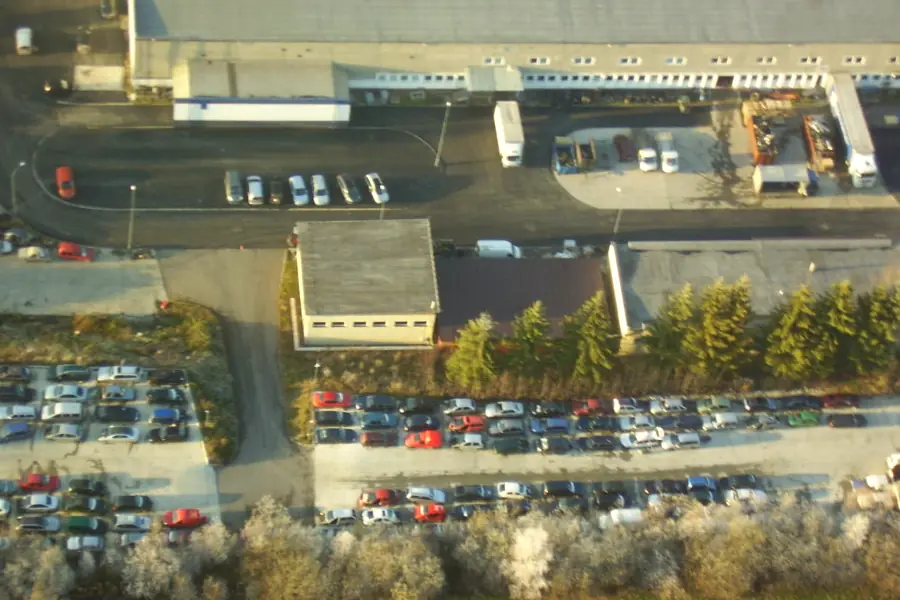 Pohľad z výšky na budovy areálu a rady odstavených vozidiel.