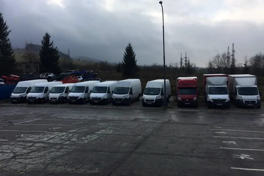 Rad dodávkových vozidiel odstavených na ploche areálu.